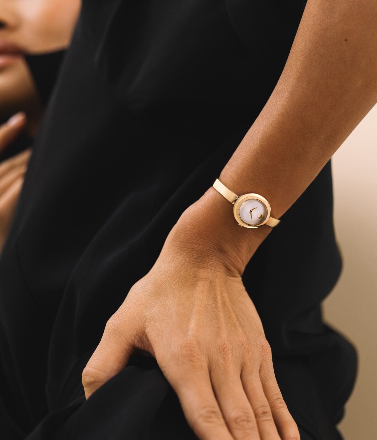 Woman wearing a Museum Bangle watch with gold tone bracelet and oval shaped white dial.