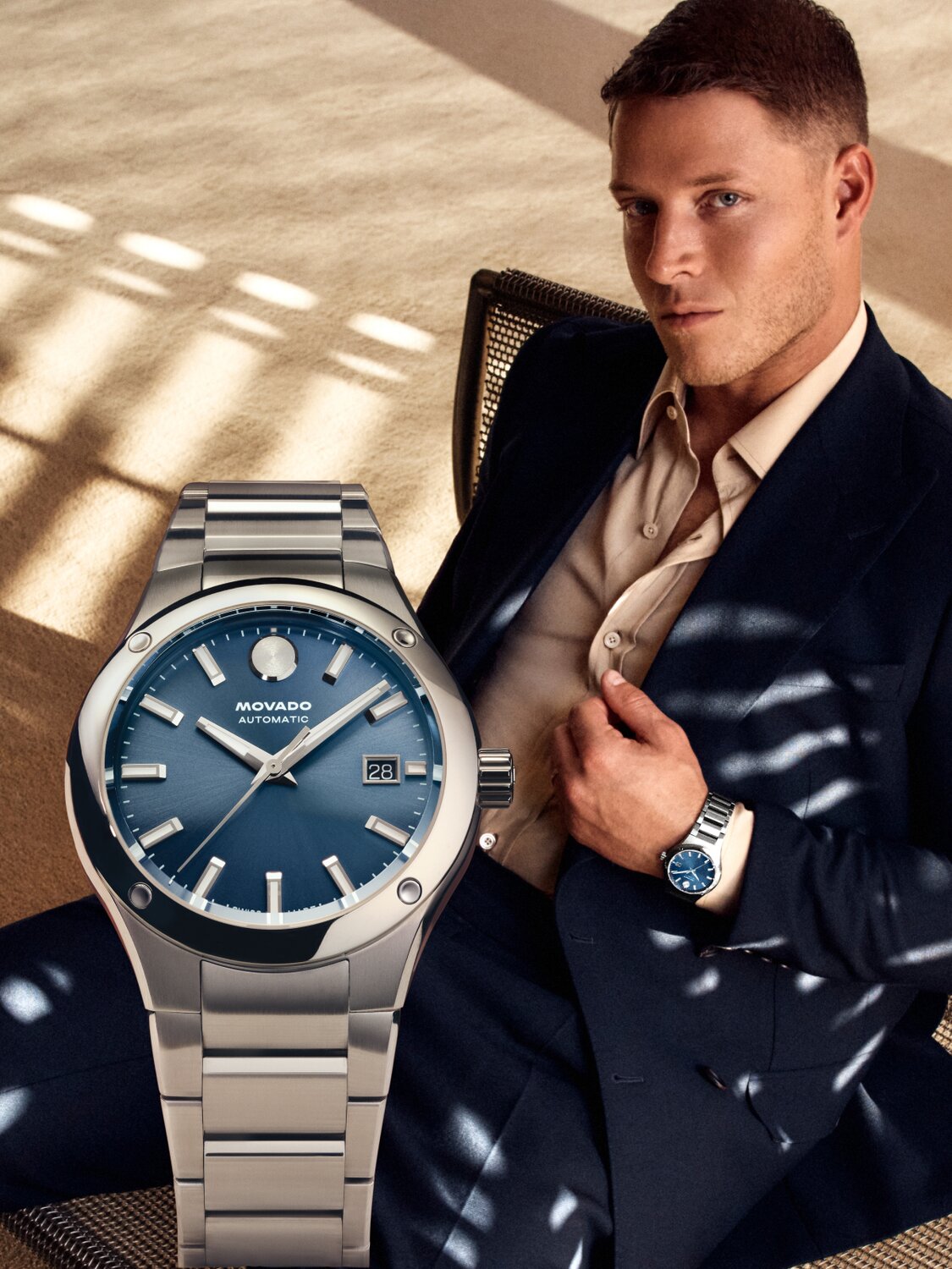 Christian McCaffrey sitting in a chair, wearing a suit and the Museum Imperiale watch with stainless steel bracelet and blue dial.