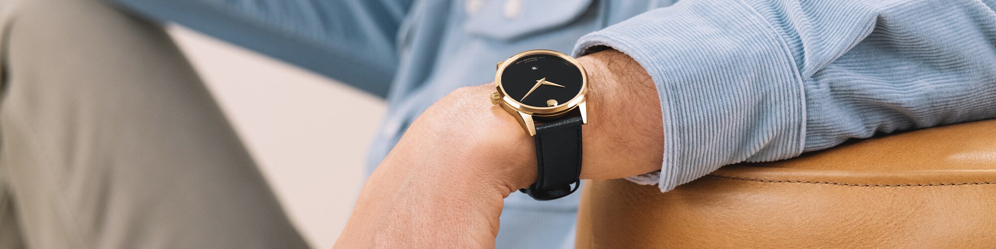 Man in a blue shirt wearing a black Museum Classic leather watch