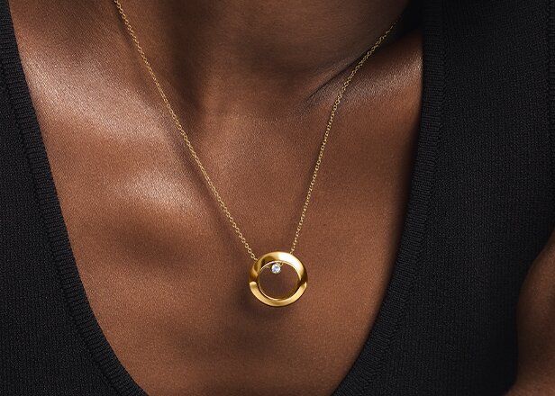 Woman wearing the gold tone Ono necklace with lab grown diamond.