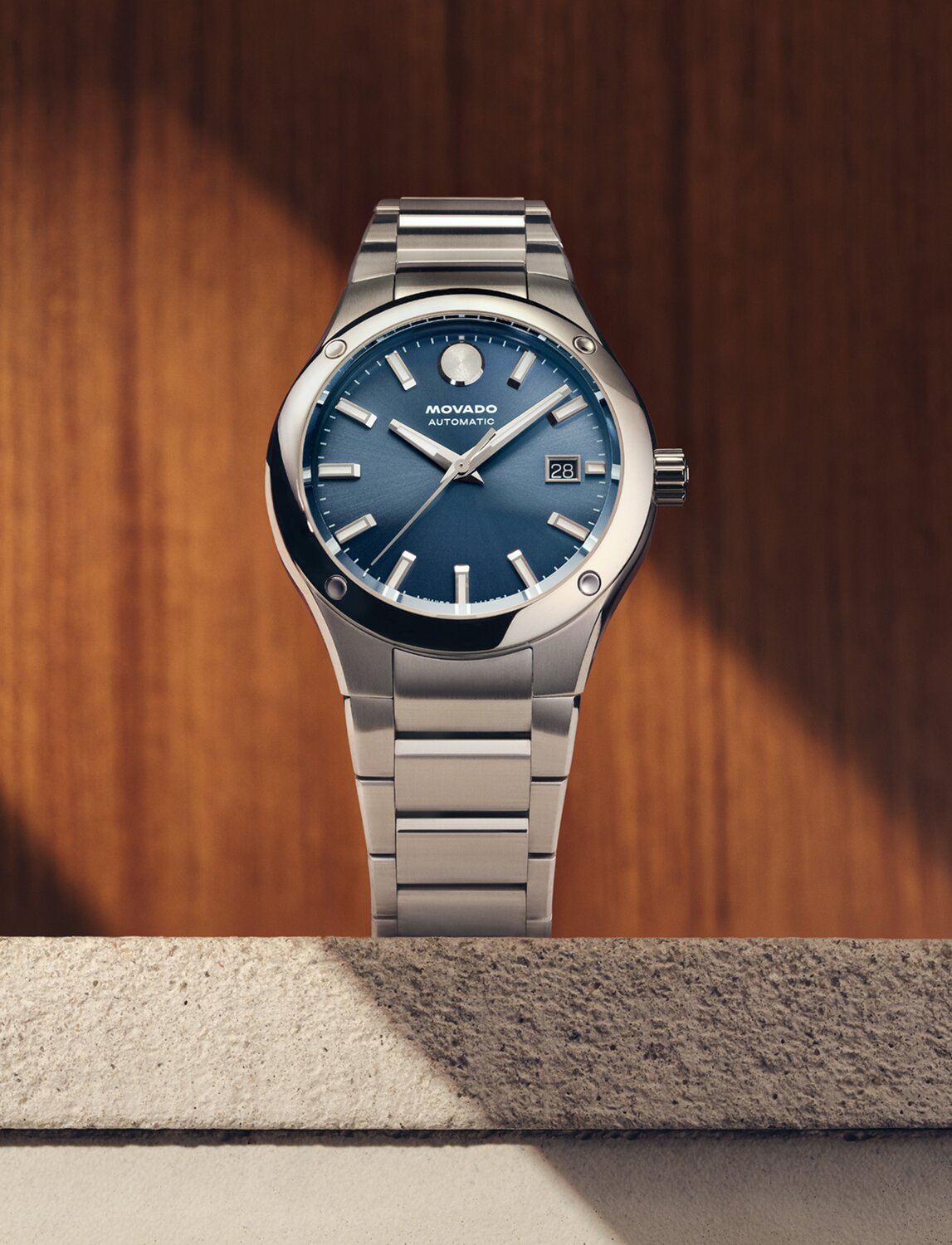 Museum Imperiale watch with silver bracelet and blue dial sitting on a stone ledge in front of a wooden wall