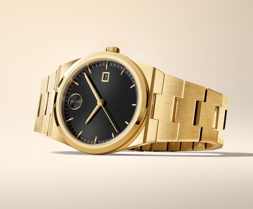 BOLD Quest watch with gold tone bracelet and black dial laying on its side.