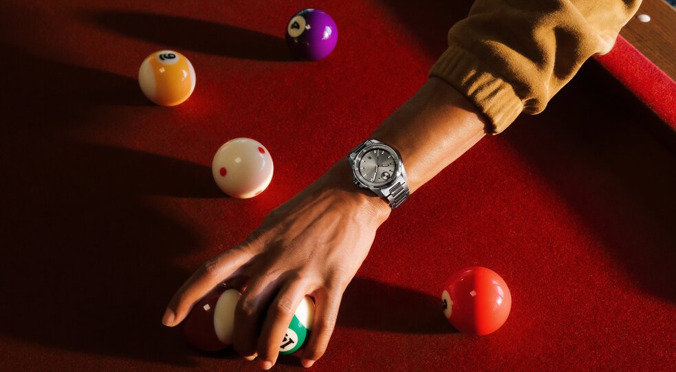 Man wearing the grey BOLD Verso S watch reaching over a pool table.