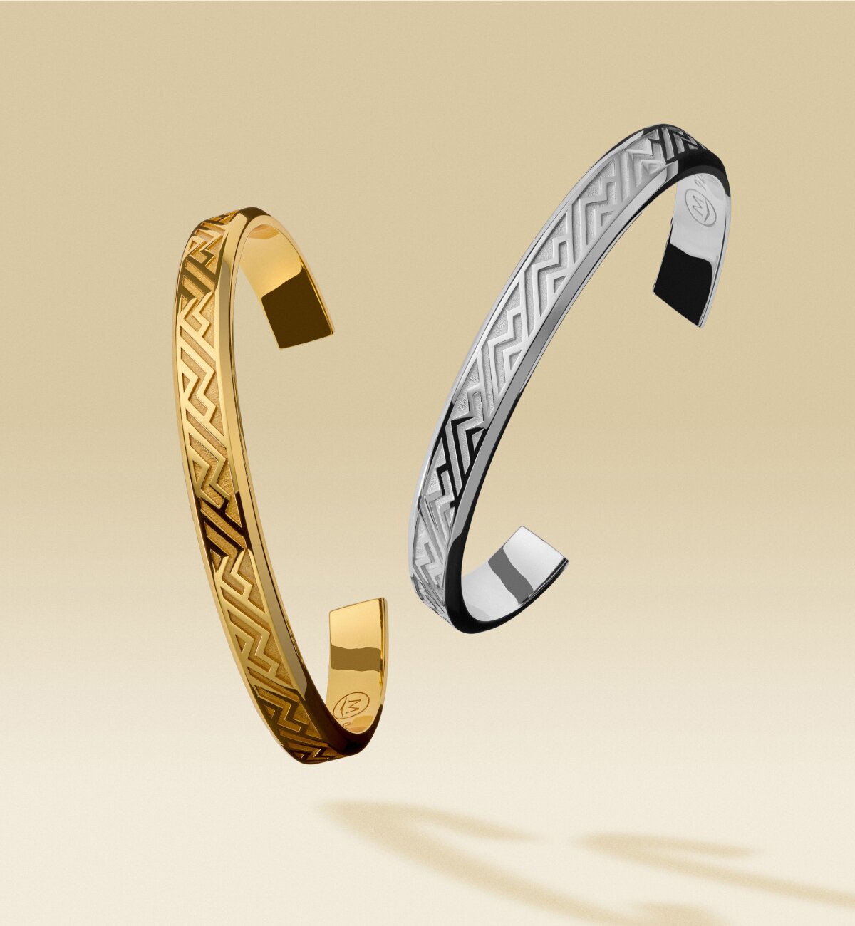 Gold tone men's cuff floating next to a silver men's cuff