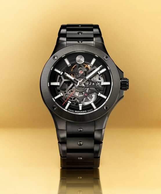 Black PVD Alta SE bracelet watch with skeleton dial in front of a yellow background.