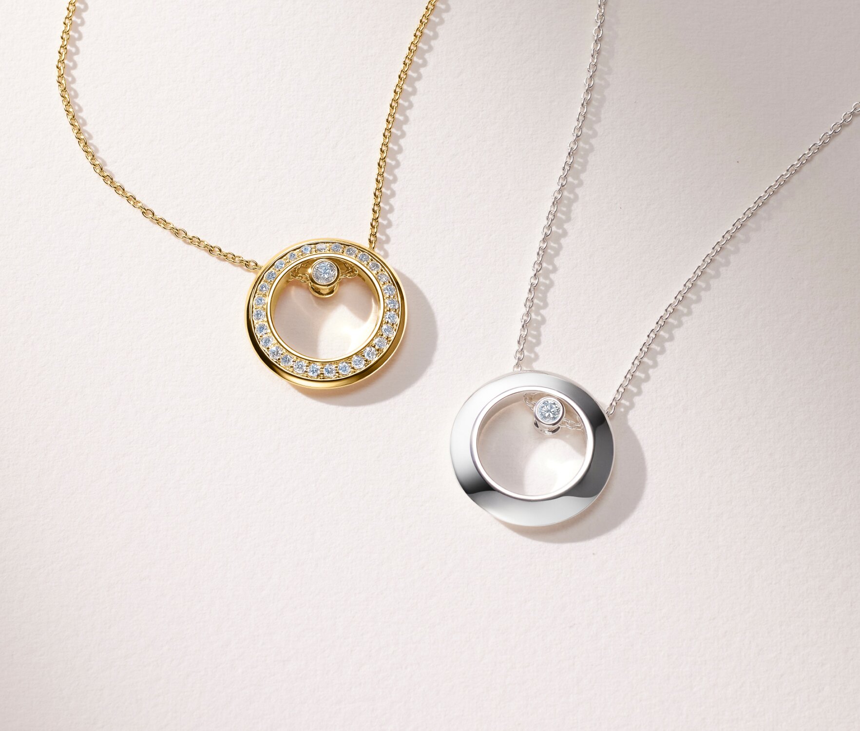Gold tone women's Ono Necklace with lab grown diamonds next to a sterling silver Ono necklace with one lab grown diamond.