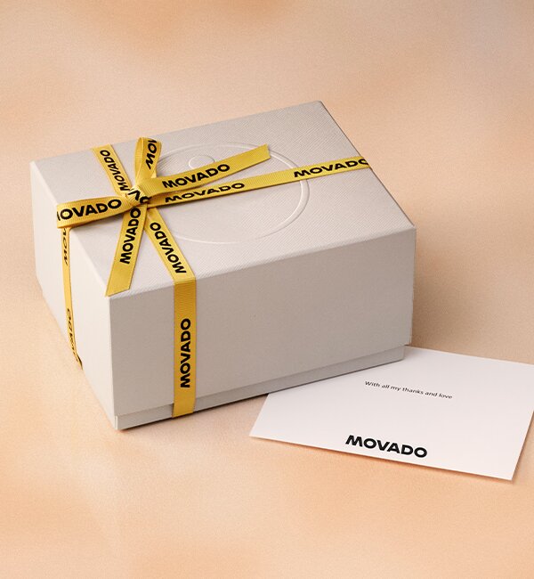 Movado white gift box with branded yellow ribbon and note card with Movado logo
