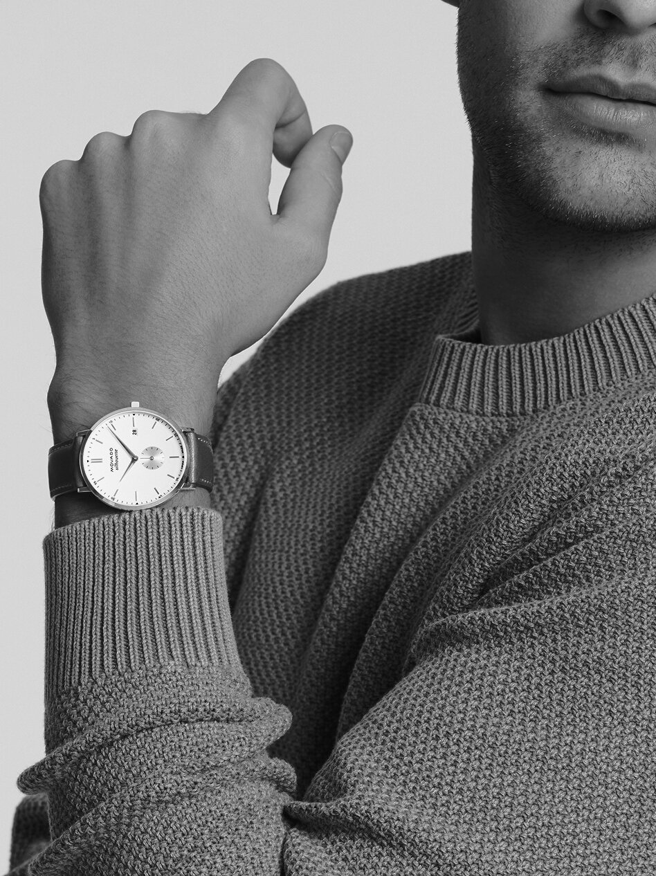 Man in a blue sweater wearing a Heritage Silhouette watch with brown strap and white dial.