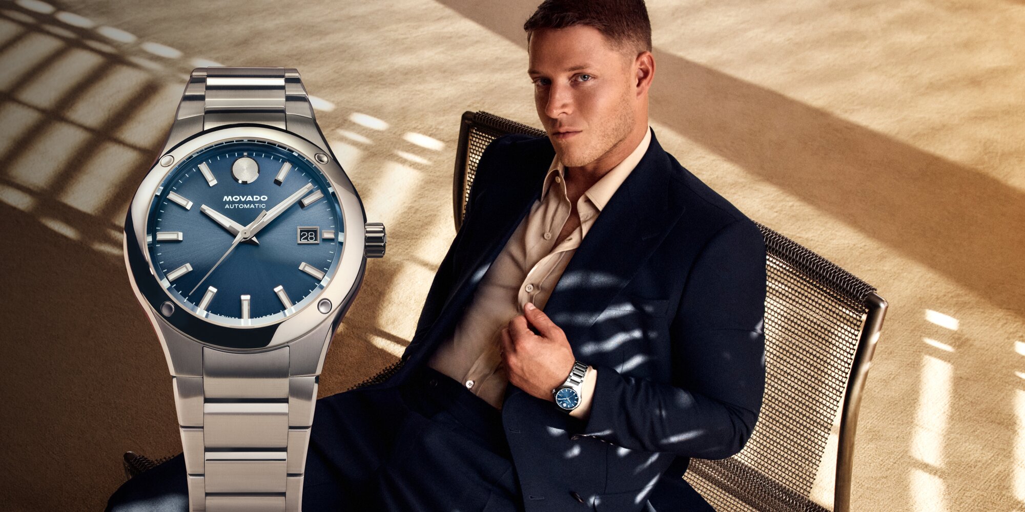 Christian McCaffrey sitting in a chair, wearing a suit and the Museum Imperiale watch with stainless steel bracelet and blue dial.