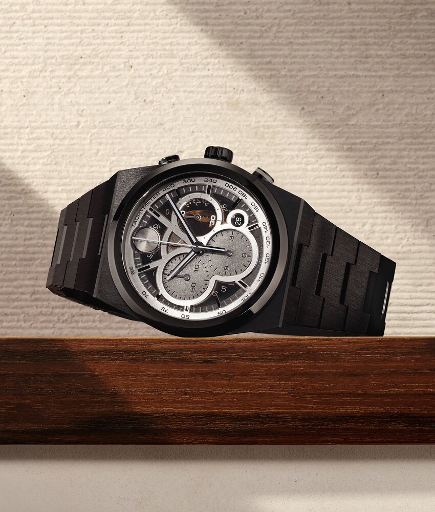 Black BOLD Quest Skeleton bracelet watch laying on its side on a wooden ledge in front of a tan background