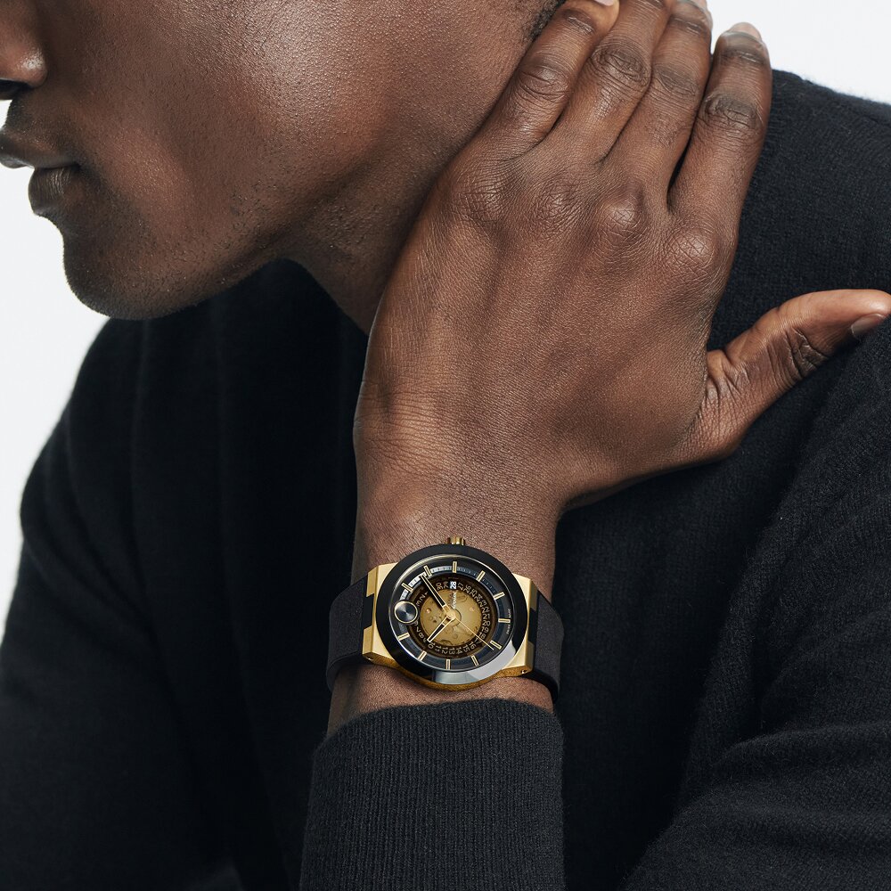 Man in a black sweater with his hand on his neck wearing the black BOLD Fusion watch with rubber bracelet and skeleton dial.