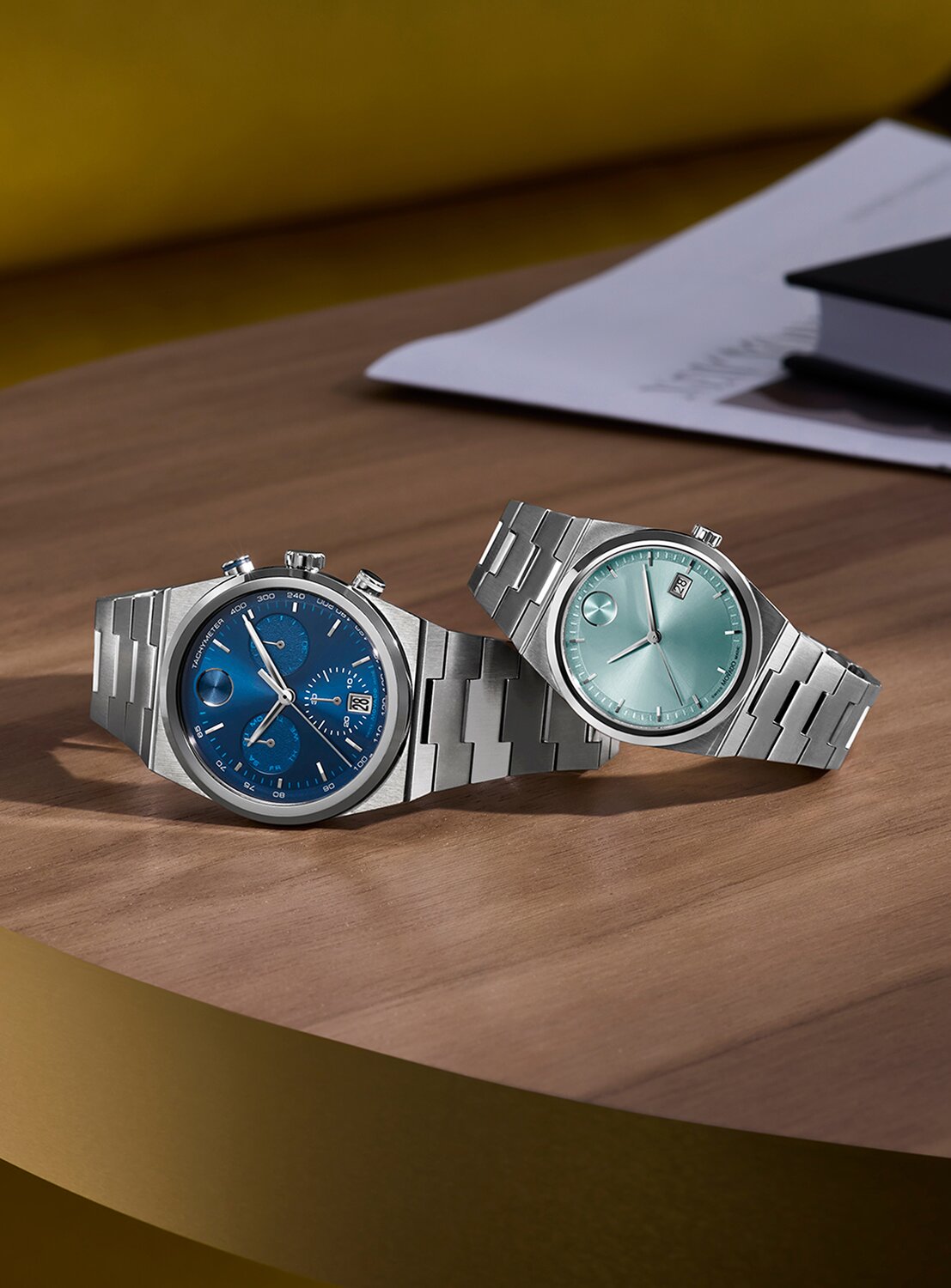 BOLD Quest chronograph watch with stainless steel bracelet and blue dial laying under a BOLD Quest stainless steel watch with light blue dial