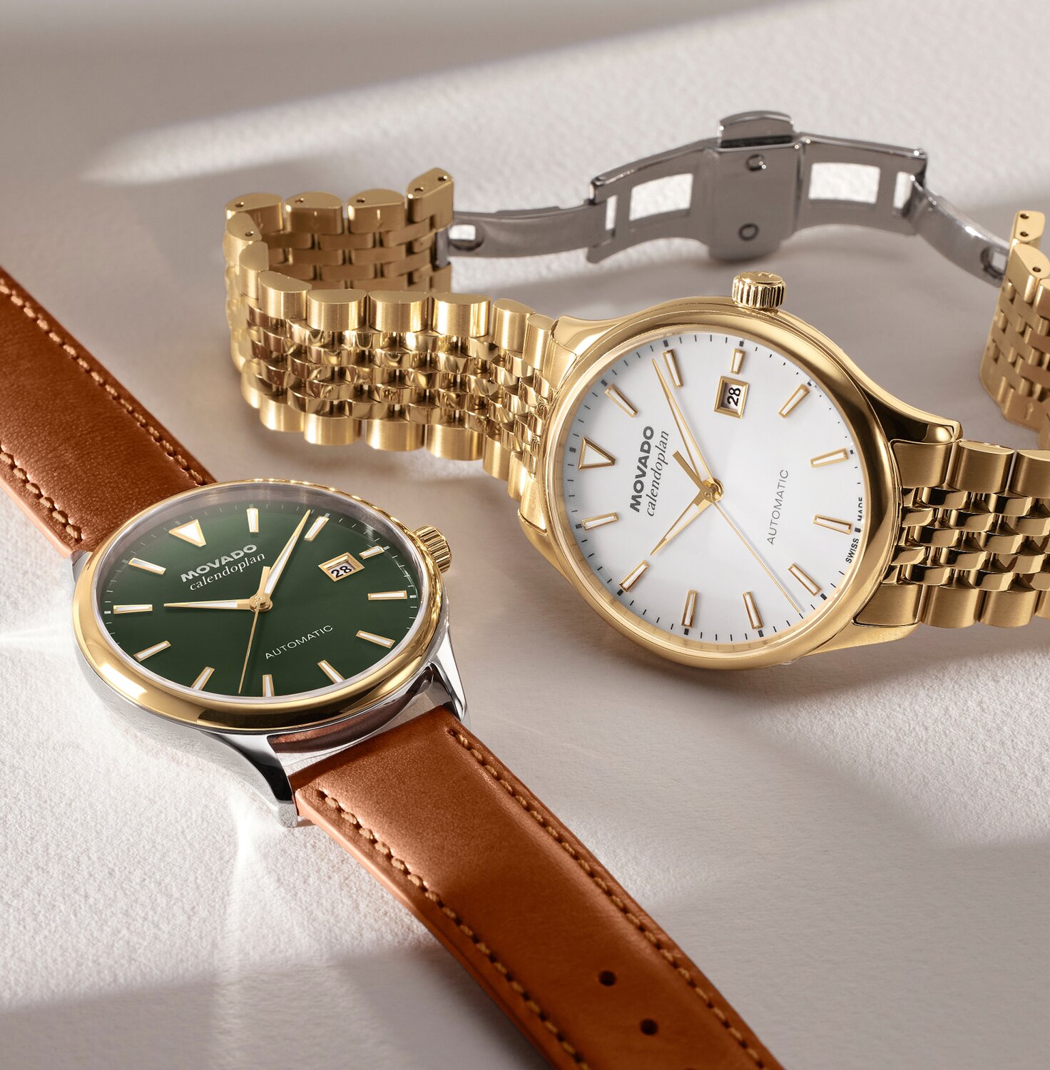 Heritage Calendoplan watch with brown leather strap and green dial next to the Heritage Calendoplan watch with gold tone bracelet and white dial.