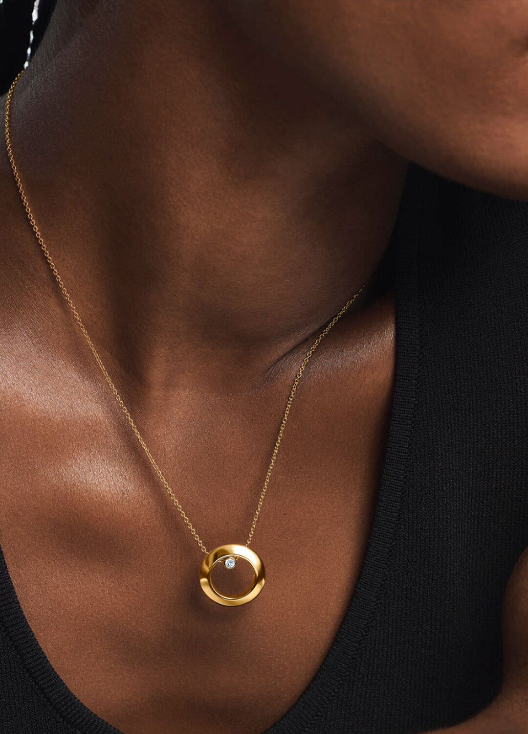 Woman wearing a gold tone necklace with a lab grown diamond.