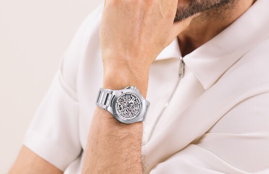 Man in a white shirt wearing the stainless steel Alta SE bracelet watch with skeleton dial.