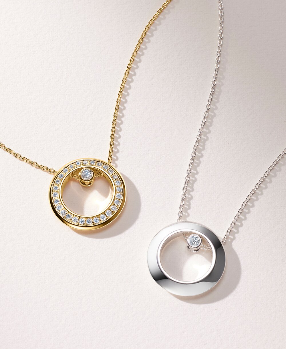 Women's Ono necklace in 18k gold vermeil with lab grown diamonds is laying next to the sterling silver Ono necklace with one lab grown diamond.