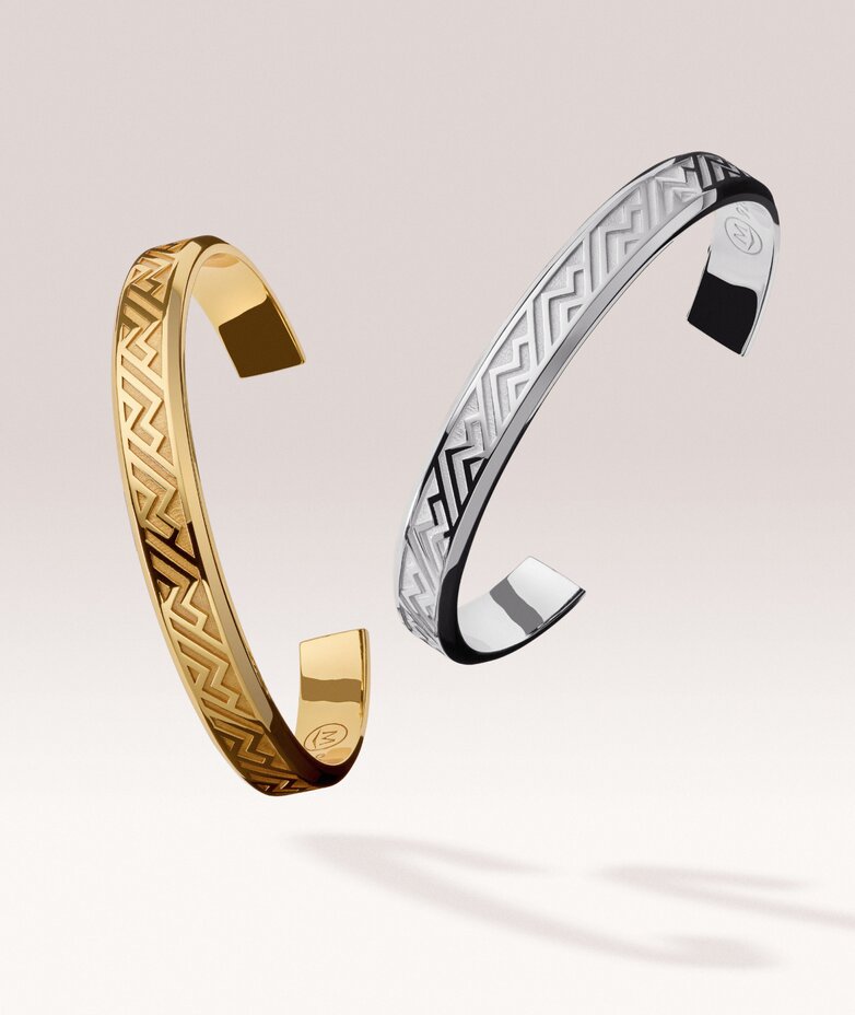 Gold tone men's cuff floating next to a silver men's cuff