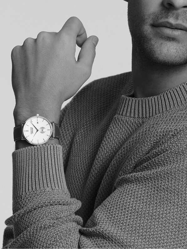 Man in a blue sweater wearing a Heritage Silhouette watch with brown strap and white dial.