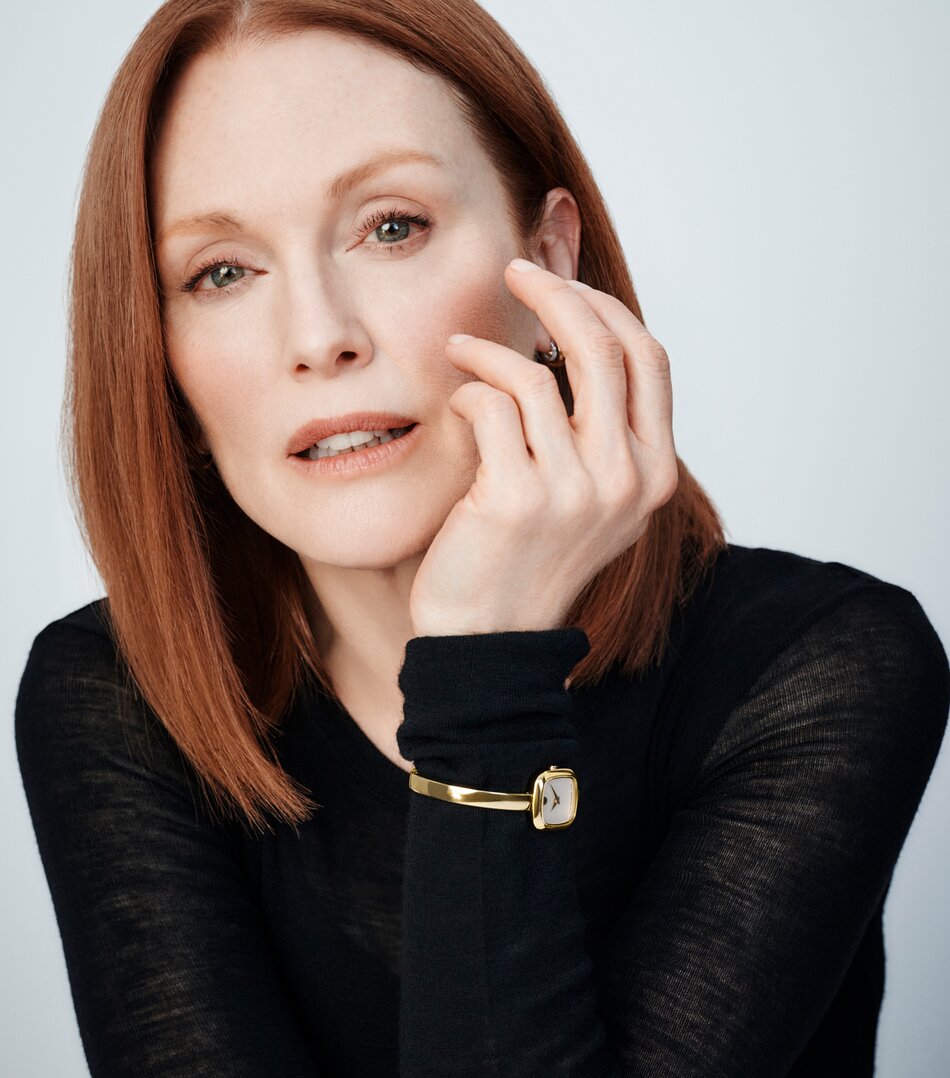 Julianne Moore in a black top wearing the gold tone Museum Bangle watch with square white dial.