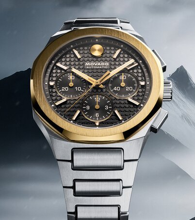 Two Tone Alta Centurion bracelet watch with 18K Gold Bezel in front of mountains.