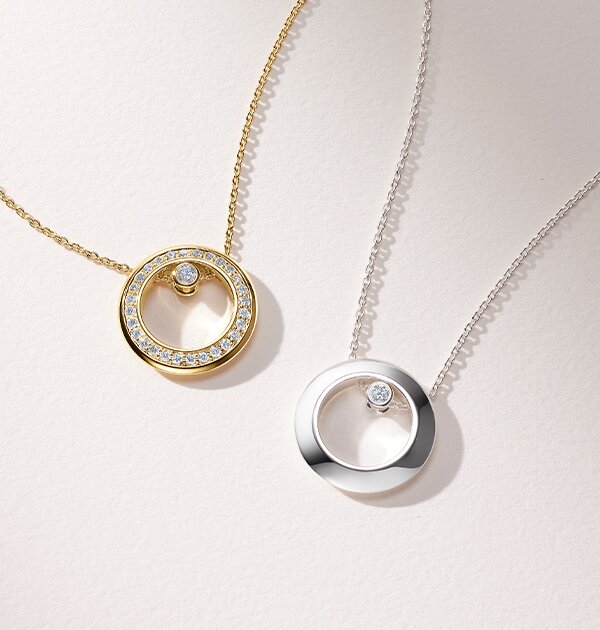 Gold tone Ono necklace with lab grown diamonds next to a silver Ono necklace with one lab grown diamond. 