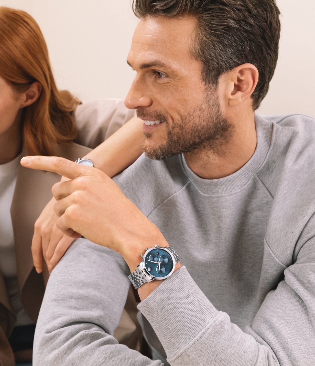 Man in a grey long sleeve shirt wearing a Museum Classic with stainless steel bracelet and blue chronograph dial.