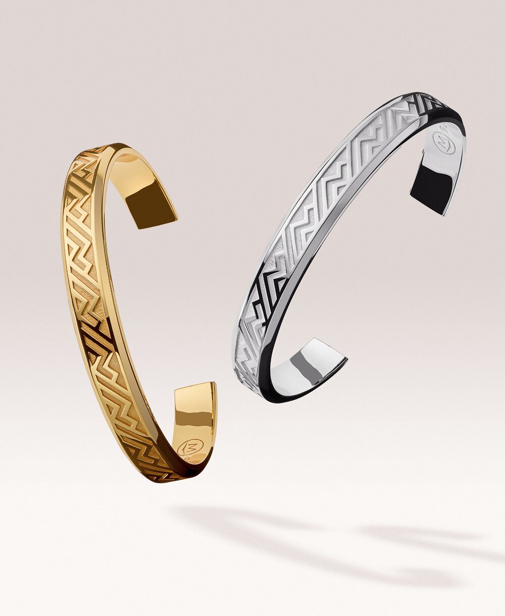 Gold tone men's cuff floating next to a silver men's cuff