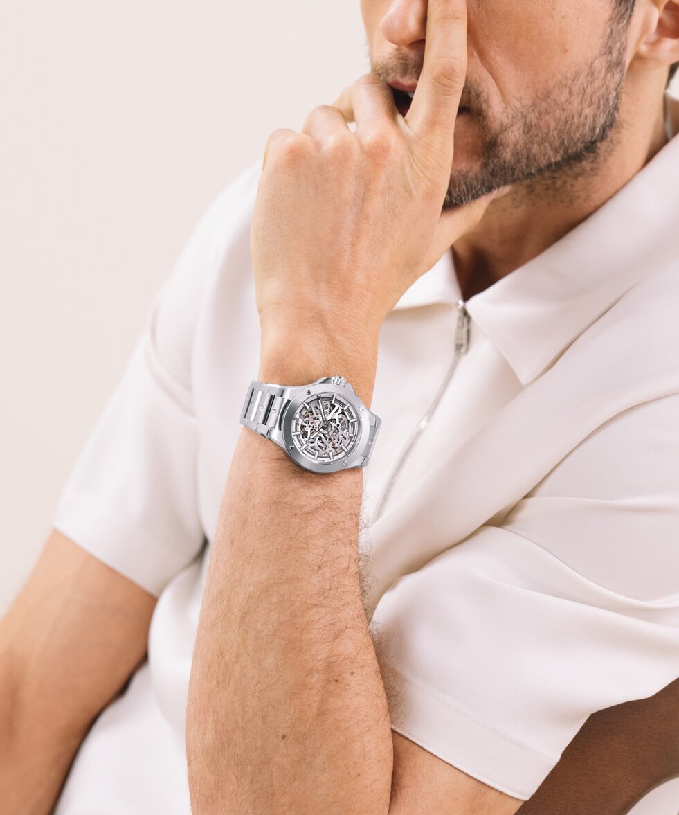 Man in a white shirt wearing the stainless steel Alta SE bracelet watch with skeleton dial.