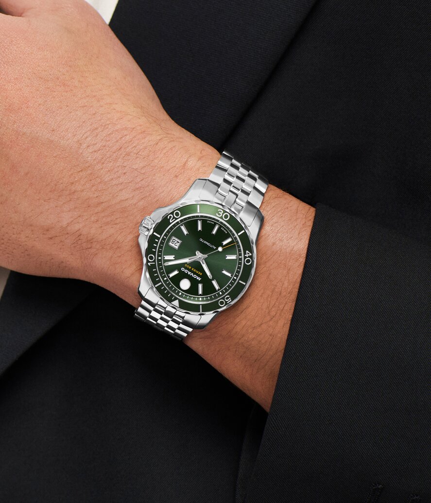 Man wearing the Series 800 stainless steel bracelet watch with green dial.