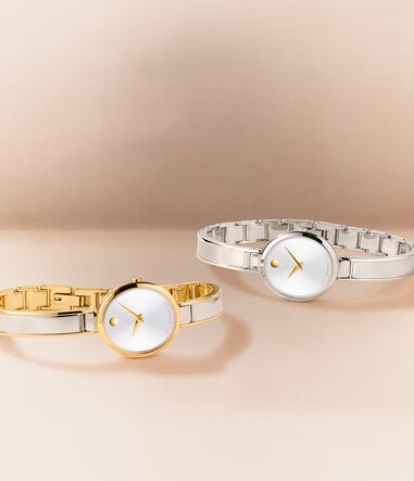 Two tone Moda bangle watch laying in front of a silver Moda bangle watch with gold accents.