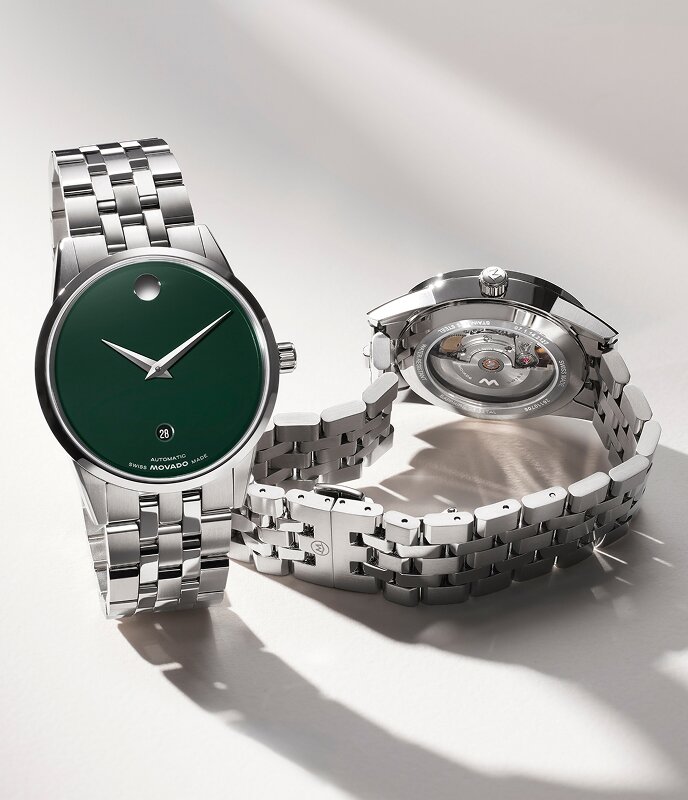 Front of a Museum Classic watch with stainless steel bracelet and green dial next to the back of the watch that has an exposed case back.