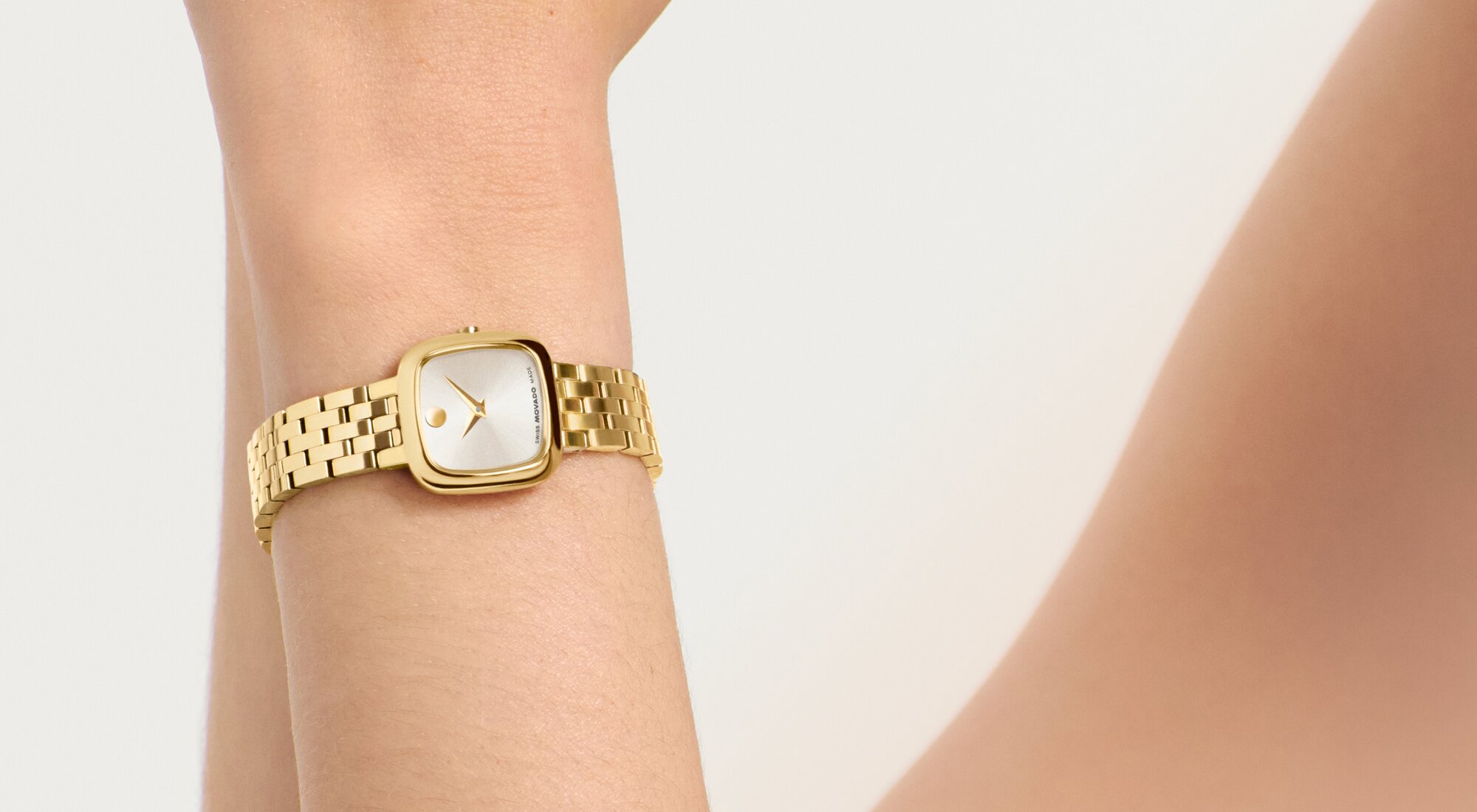 Gold tone Museum Classic bracelet watch with square dial on a woman's wrist.
