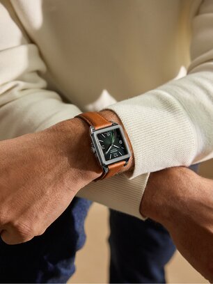 Man in a white sweater wearing the Heritage 1917 watch with brown leather strap and green square dial.