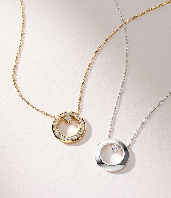 Gold plated Ono necklace with lab grown diamonds next to a silver Ono necklace with one lab grown diamond. 