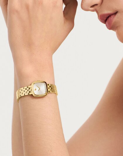 Woman wearing the gold tone Museum Classic bracelet watch with square dial.