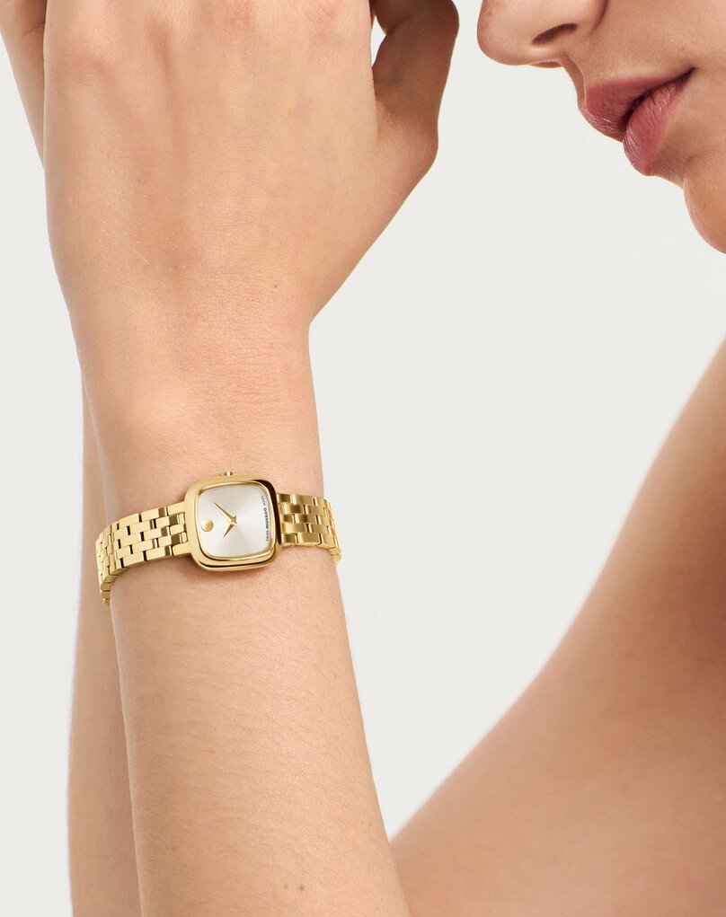 Woman wearing the gold tone Museum Classic bracelet watch with square dial.