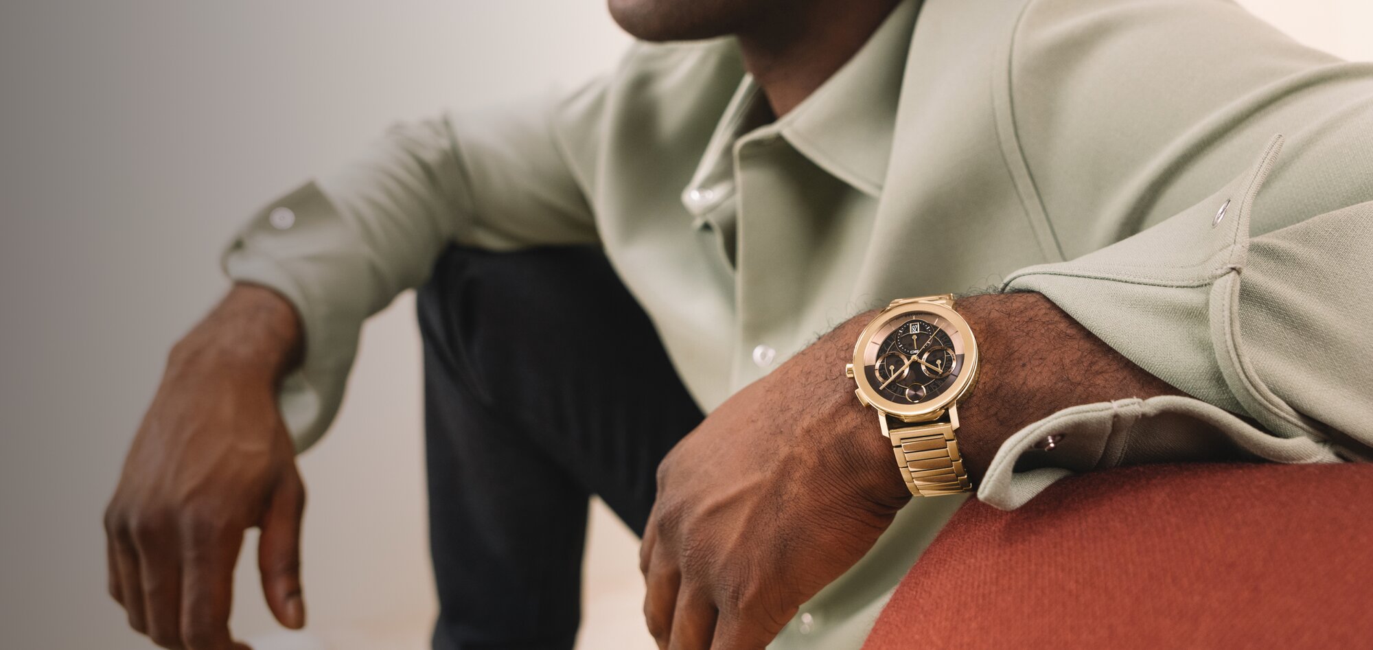 Man in button down wearing a BOLD Evolution 2.0 watch with gold tone bracelet and brown skeleton, chronograph dial. 