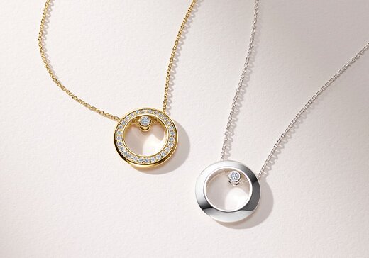 Gold tone Ono necklace with lab grown diamonds next to a silver Ono necklace with one lab grown diamond. 
