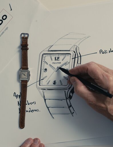 Person sketching out the updated Heritage 1917 watch while referencing the original Heritage 1917 watch with brown strap and square dial.
