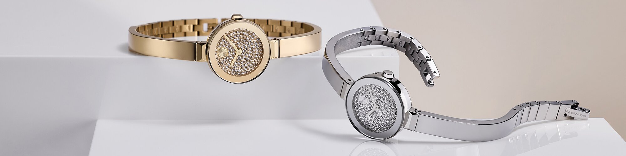 Gold tone and stainless steel BOLD Bangle Mini watches with crystal dials laying next to one another.
