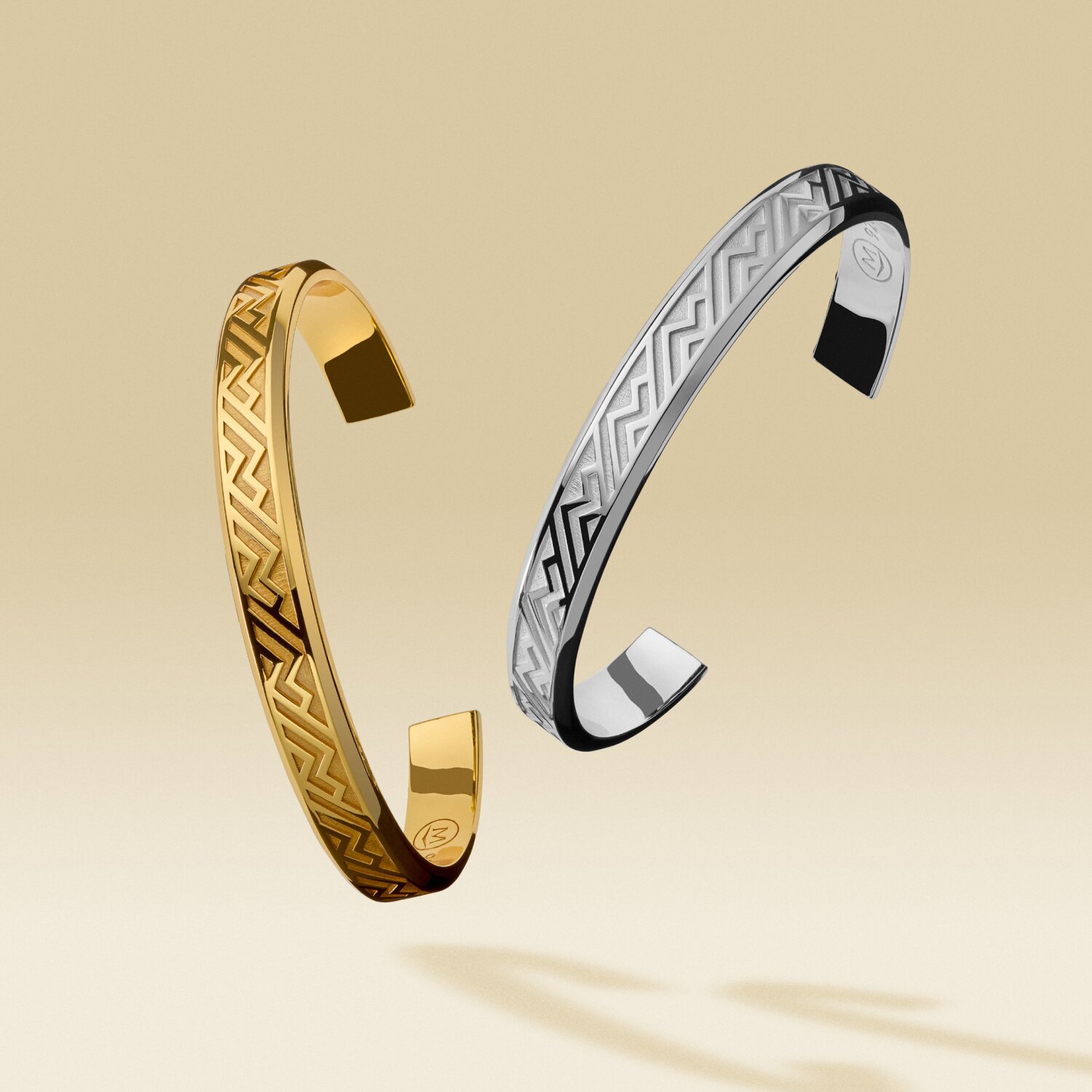 Gold tone men's cuff floating next to a silver men's cuff
