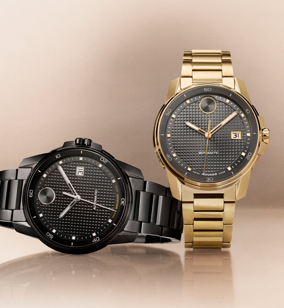 Black BOLD Verso Automatic bracelet watch laying next to a gold tone BOLD Verso Automatic bracelet watch with grey dial