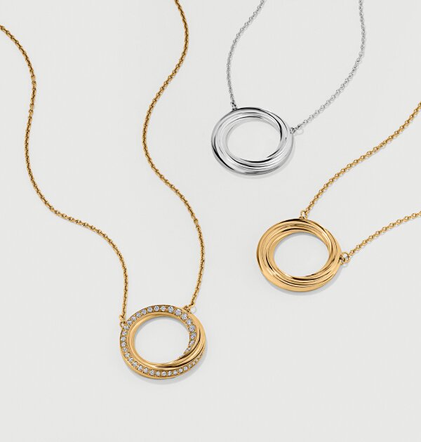 Gold tone necklace with fleur charm next to silver fleur charm necklace