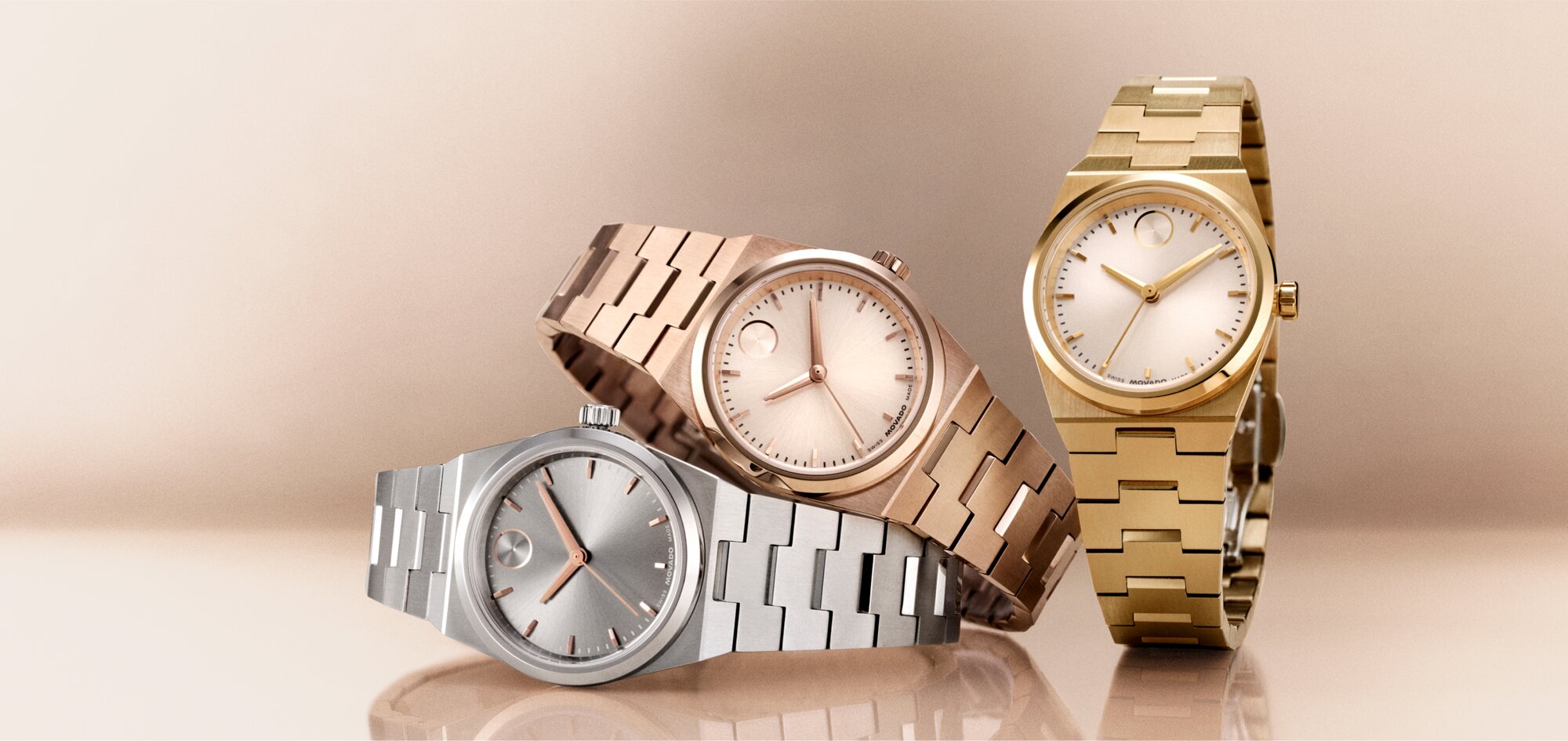 Rose gold tone BOLD Quest Mini watch laying on top of a silver BOLD Quest Mini watch with a gold tone BOLD Quest mini watch to the right.