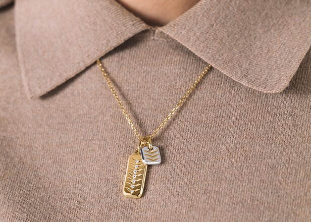 Two tone chevron charm necklace on a brown collared shirt