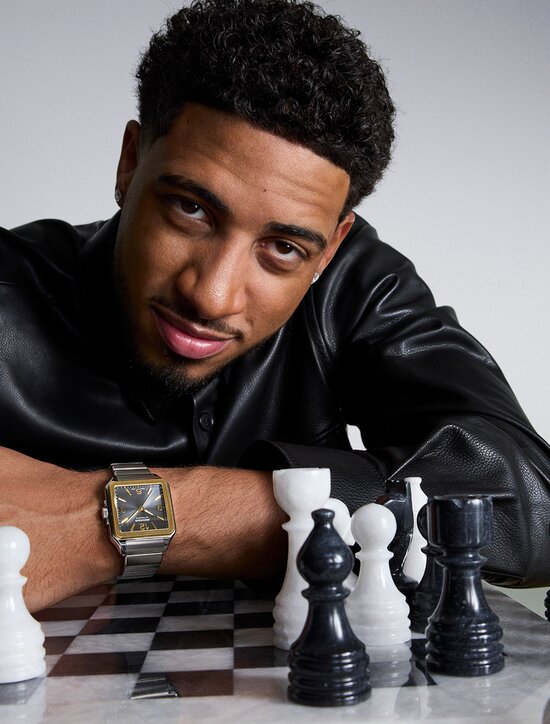 Tyrese Haliburton wearing white tank top and blue cardigan, holding a black basketball, wearing the silver SE Diver Automatic watch with blue dial.