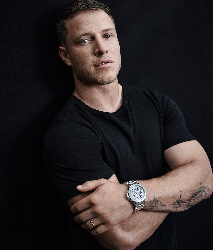Christian McCaffrey in a black t-shirt with his arms crossed wearing a silver Alta SE Skeleton watch