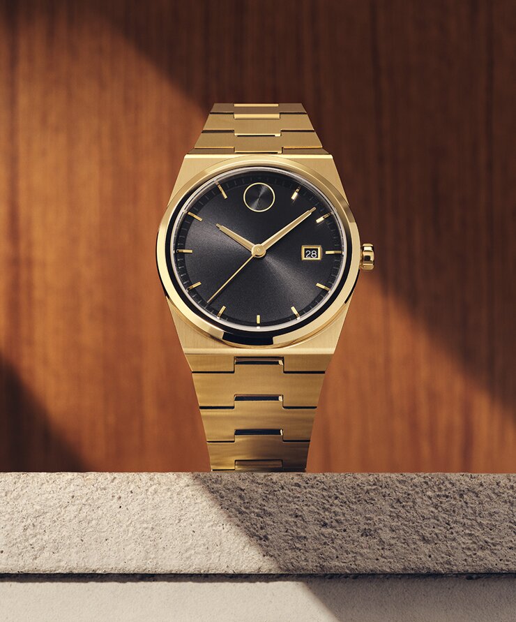 Ludacris wearing a white suit, sitting in a car, wearing the BOLD Quest watch with gold tone bracelet and black dial.