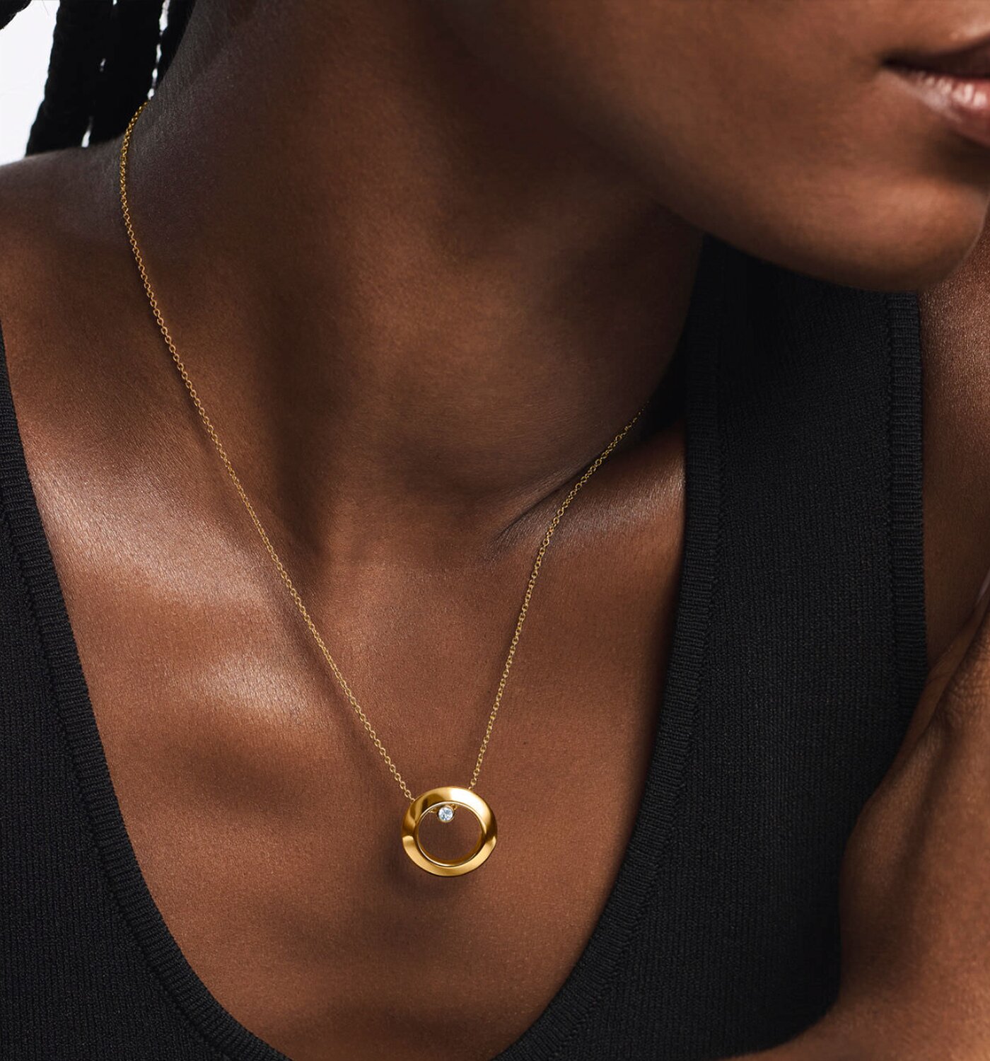 Woman wearing a gold tone necklace with a lab grown diamond.