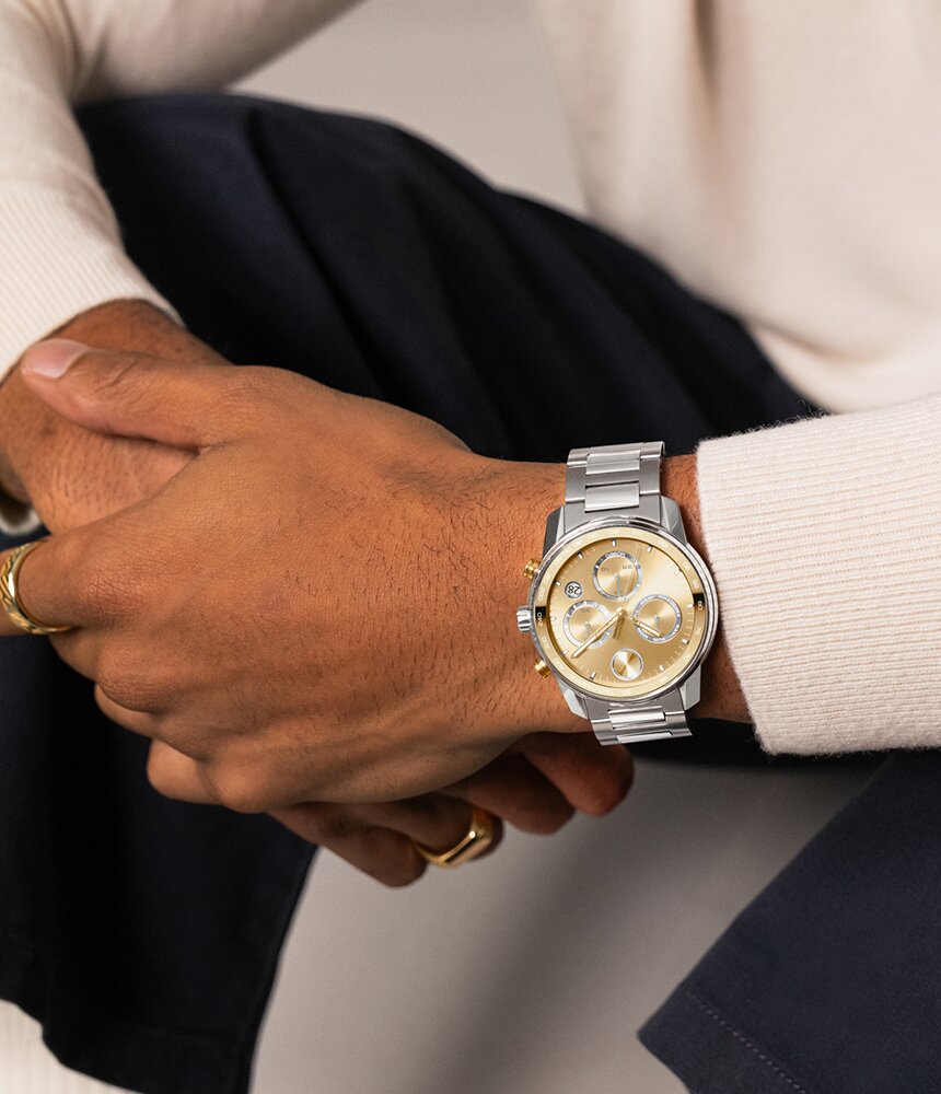 Man in a white sweater wearing the Movado BOLD Verso Chronograph watch with stainless steel bracelet and gold tone chronograph dial.